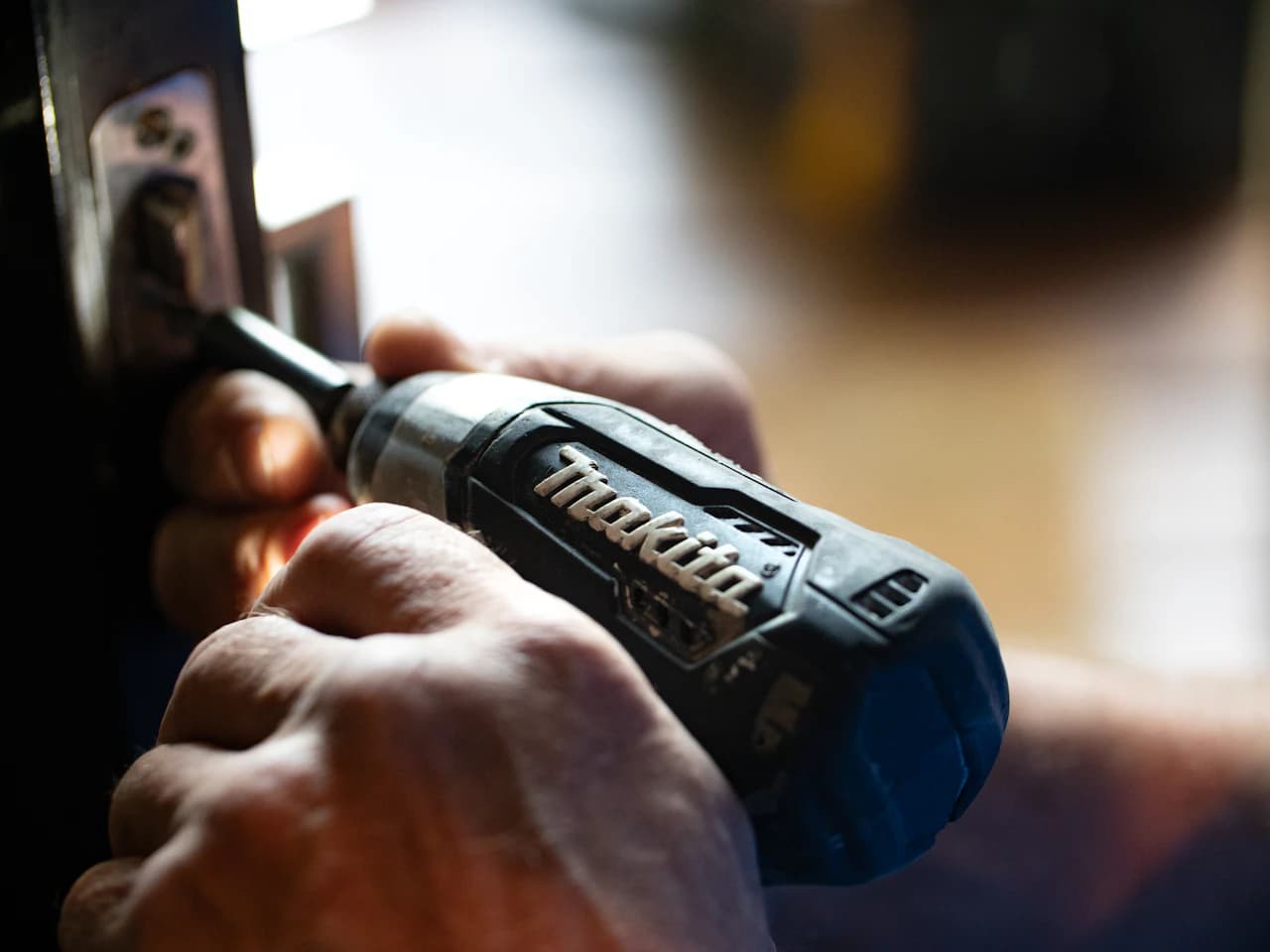 Locksmith using a power drill to install a door lock